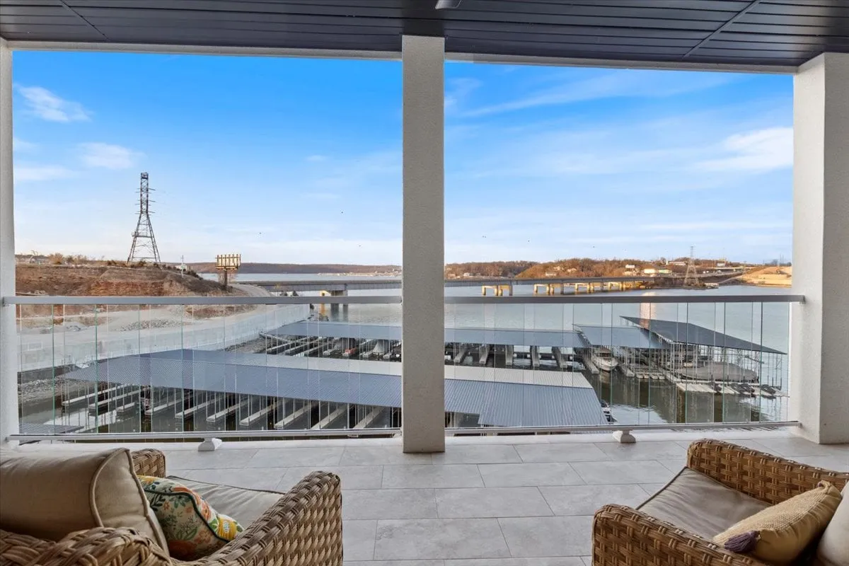 A tranquil balcony view overlooking the serene lakefront, with the marina in the distance and a soft evening glow on the water. The scene suggests a peaceful setting where guests can relax, enjoy coffee, and take in the beauty of the lake right from the privacy of their condo.