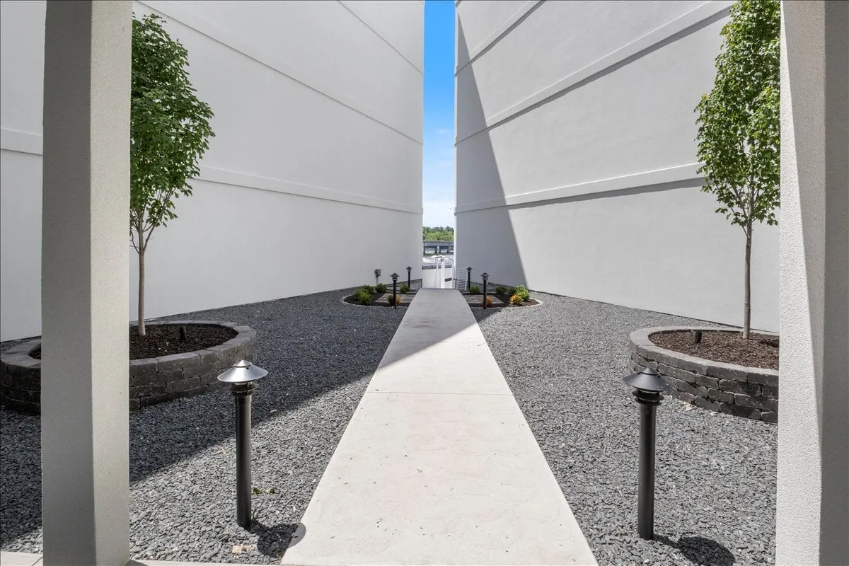 A picturesque pathway lined with greenery, trees, and tasteful lighting, leading guests through landscaped areas perfect for reflective walks or quiet conversations. The mood is calm and intimate, ideal for couples or small groups seeking tranquil moments.